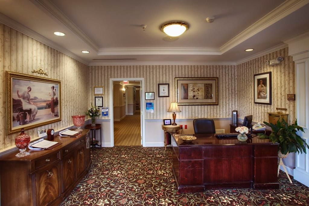 A well-decorated office space featuring a wooden desk, patterned carpet, and various decorative items.
