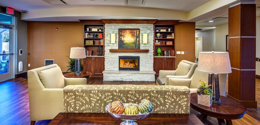 A cozy living room featuring a fireplace, flanked by bookshelves and armchairs, with a comfortable sofa and decorative elements.