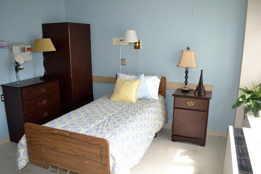 A cozy bedroom featuring a single bed, bedside lamp, and wardrobe.