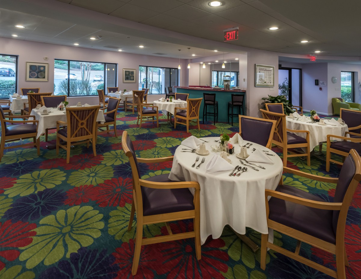 A cozy restaurant interior with neatly arranged tables and colorful carpet.