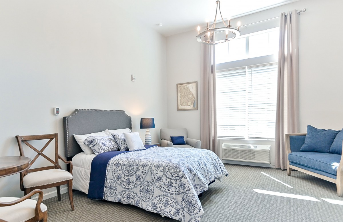 A modern bedroom with elegant decor, featuring a large window that allows natural light to fill the space.