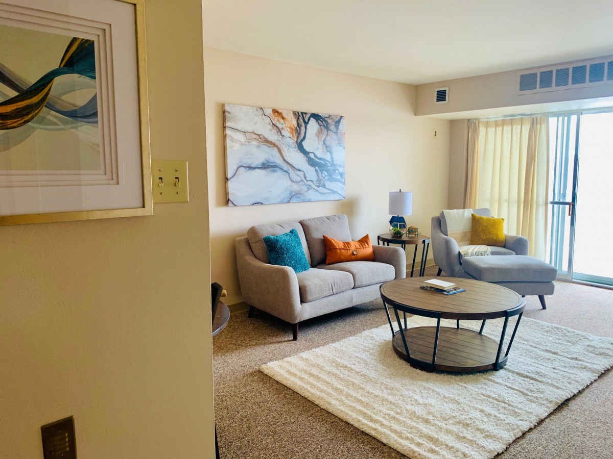 A modern and stylish living room featuring a comfortable sofa, round coffee table, and abstract artwork on the wall.