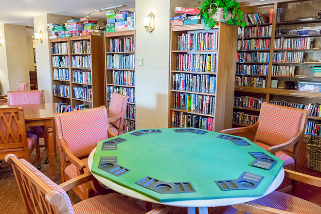 A cozy library space with bookshelves and a table set up for a card game.