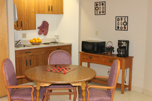 A cozy kitchen dining area featuring a round wooden table with chairs, a microwave, and a coffee maker.
