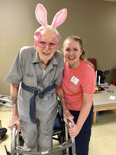 A joyful moment shared between an elderly resident and a caregiver, celebrating with bunny ears.