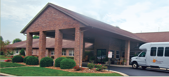 A brick building with a covered entrance and landscaped surroundings.