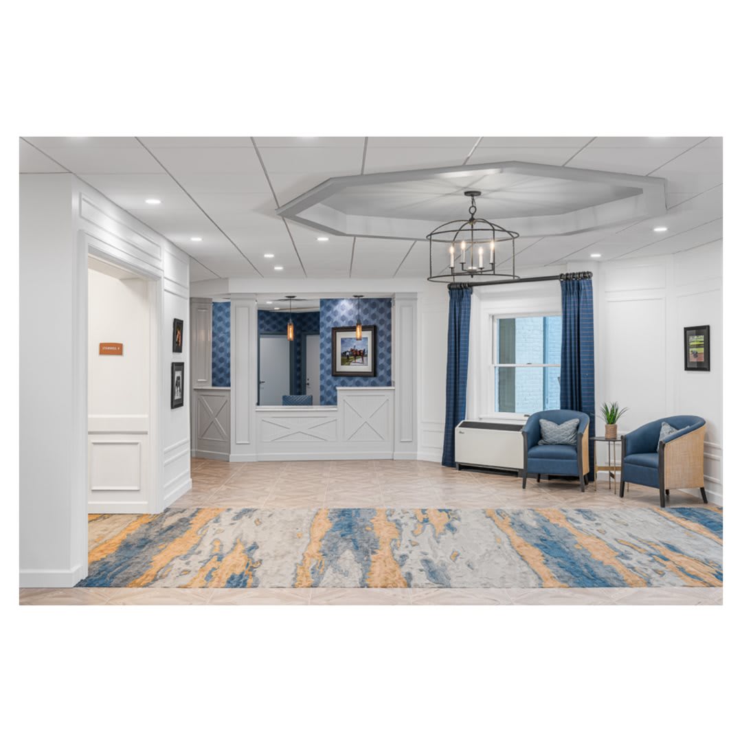A modern lobby with blue and white decor, featuring a seating area and stylish chandelier.