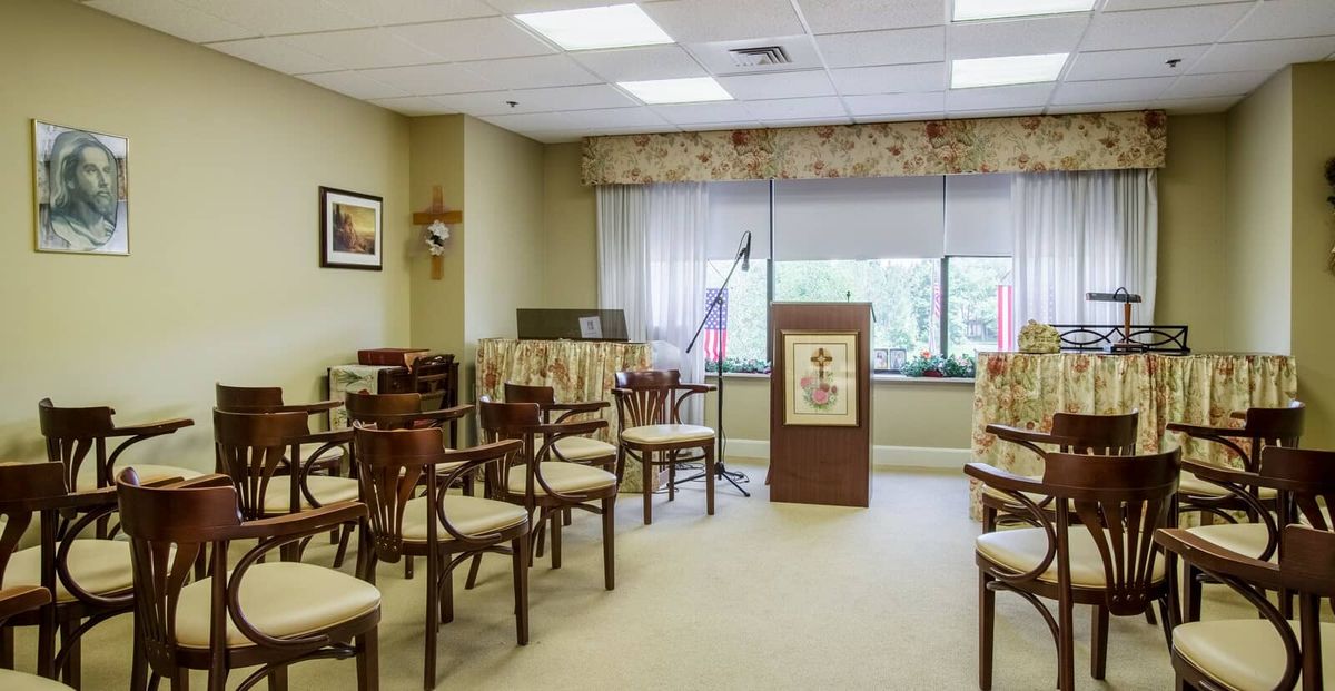 An empty room set up for a meeting or event, featuring chairs arranged in rows and a podium at the front.