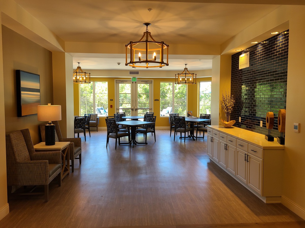 A cozy dining area with elegant lighting and natural light coming through large windows.