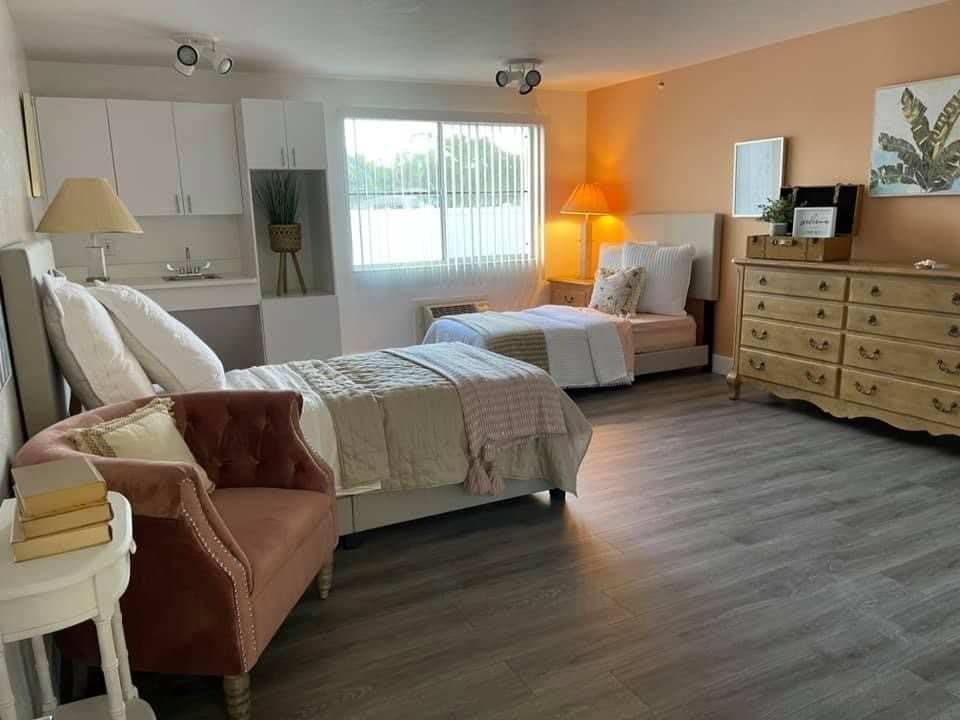 A spacious bedroom with two beds, a dresser, and modern decor.