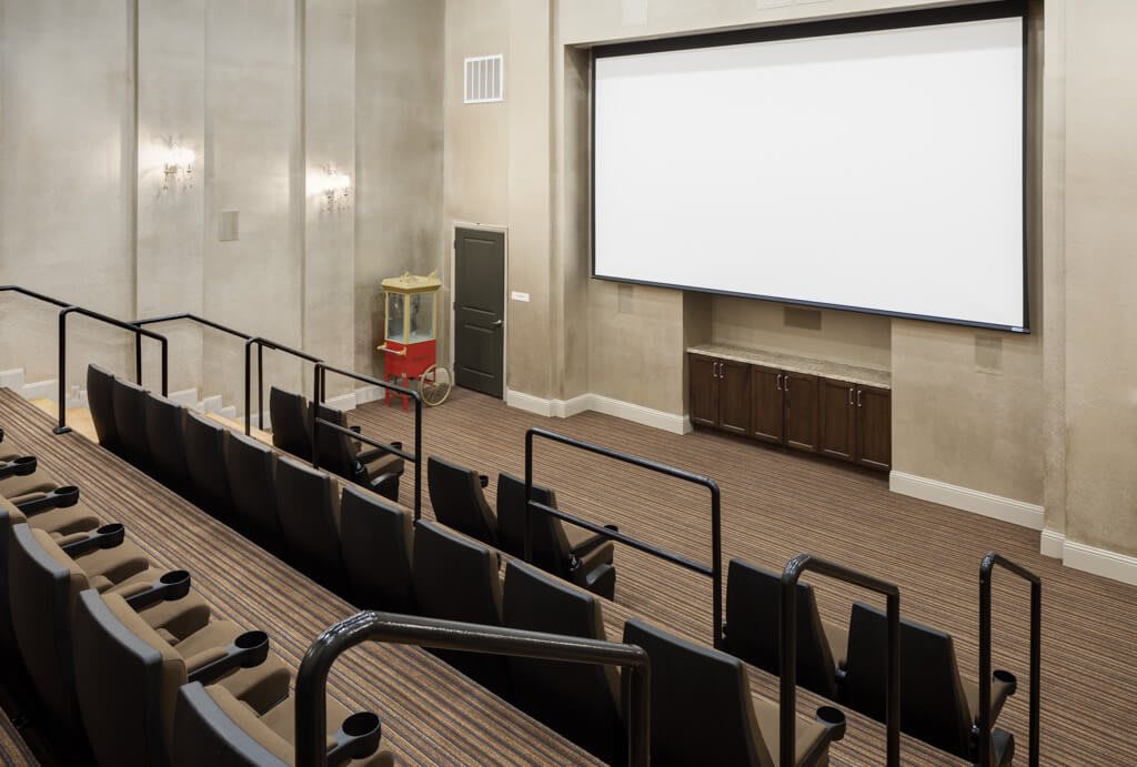 An empty theater room featuring a large screen and tiered seating.