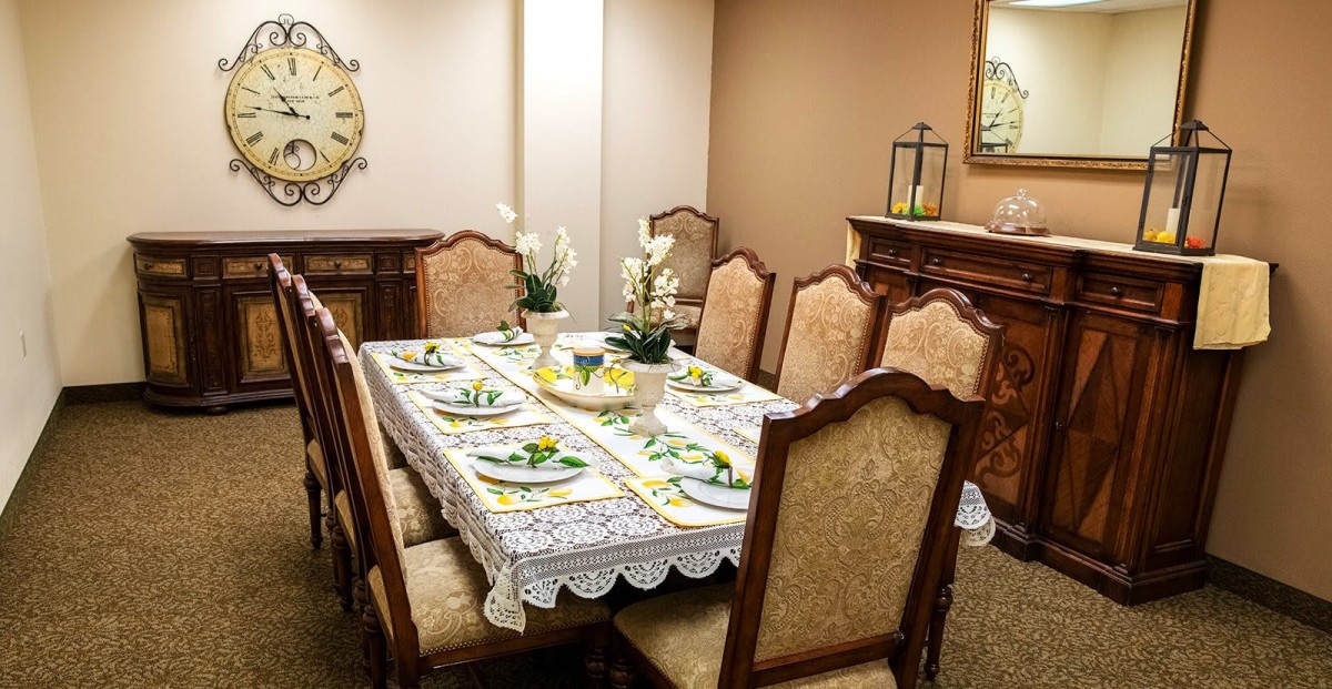 An elegantly set dining table in a well-decorated room, complete with ornate chairs and floral centerpieces.