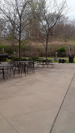 A quiet outdoor seating area featuring empty tables and chairs surrounded by trees.
