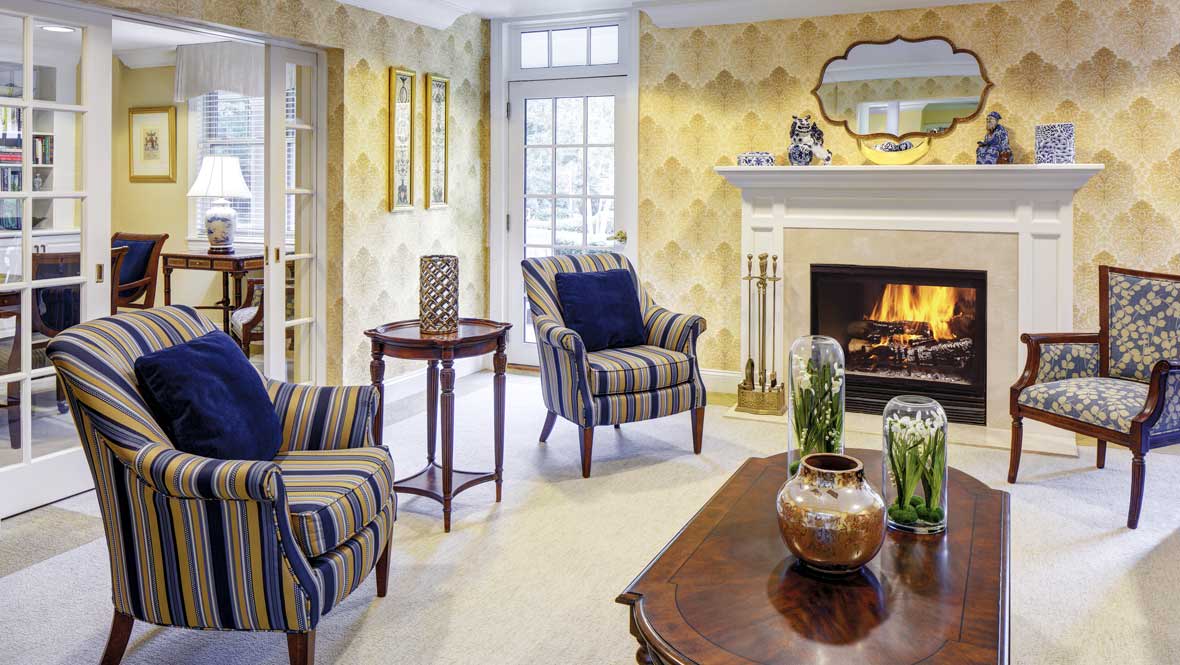 A cozy living room featuring striped armchairs, a fireplace, and elegant decor.