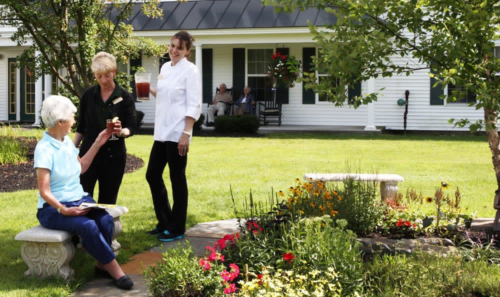 A group of people enjoying a conversation in a garden outside a house.