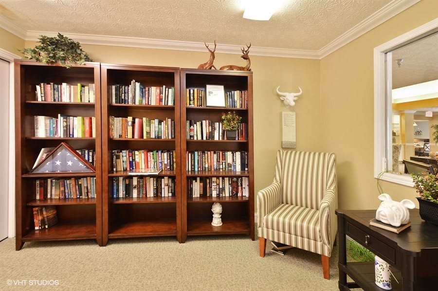 A cozy living room with wooden bookshelves filled with books and a striped armchair.