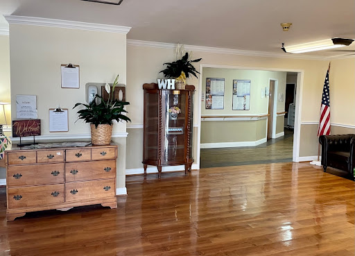 A spacious and inviting living area featuring polished wooden floors, a vintage dresser, and decorative plants.