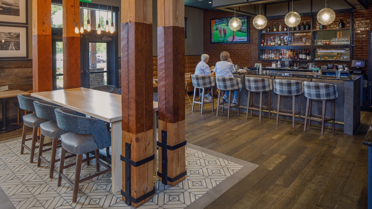 A cozy bar interior with wooden accents, seating, and a television.