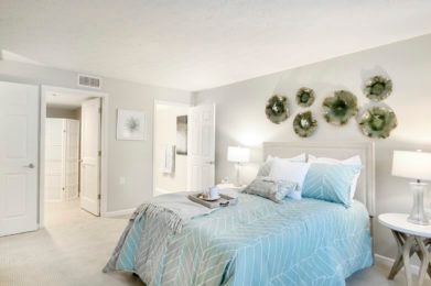A modern bedroom featuring pastel-colored bedding, decorative pillows, and simple wall art.