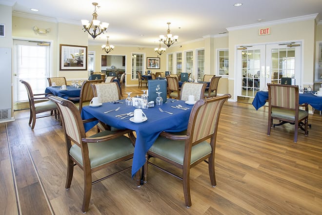 A well-lit dining area with elegantly set tables and blue tablecloths.