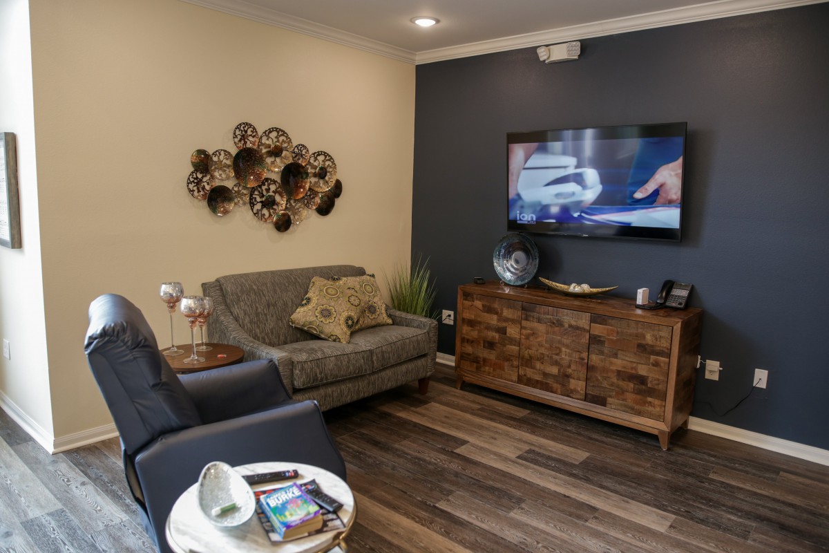A cozy living room with modern decor, featuring a television, a sofa, and wooden furniture.