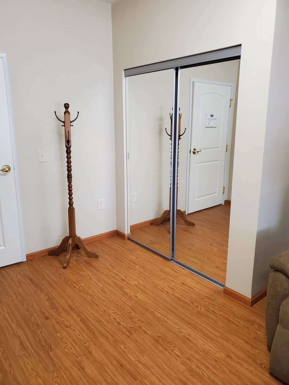 An empty room with a wooden coat rack and mirrored closet doors.