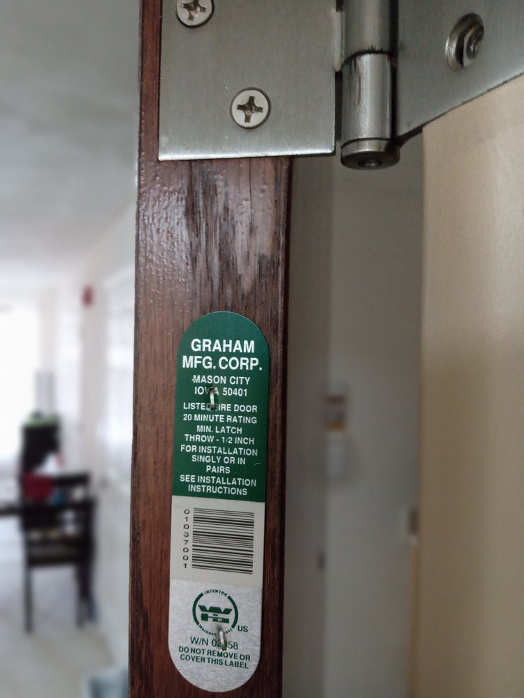 Close-up of a door with a fire safety label and hinge visible.