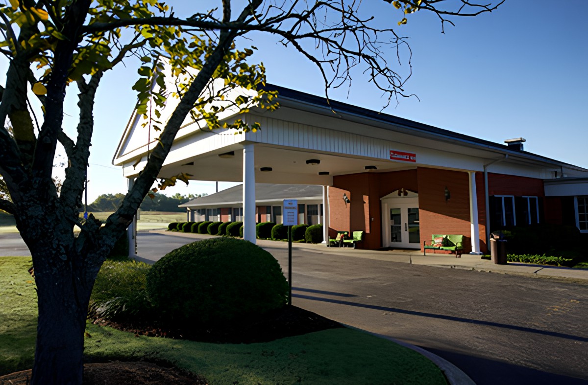 A building entrance with a covered driveway and landscaped surroundings.