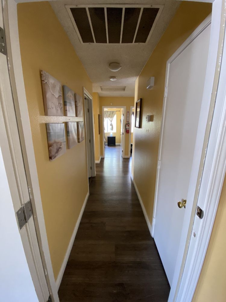 A well-lit hallway in a home, featuring wall art and multiple doors.