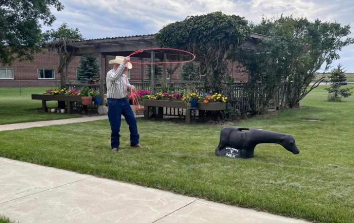 A cowboy practicing lasso skills in a garden.