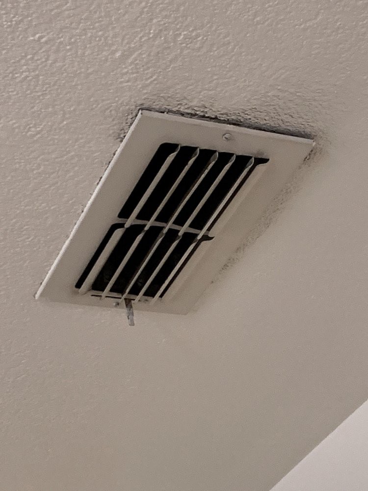 A ceiling air vent with a slightly open louvre, part of an HVAC system.
