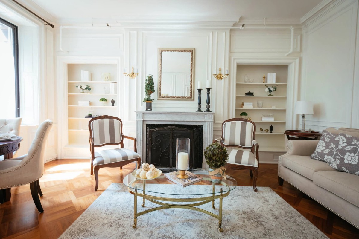A stylish living room featuring a fireplace, elegant armchairs, and a glass coffee table.