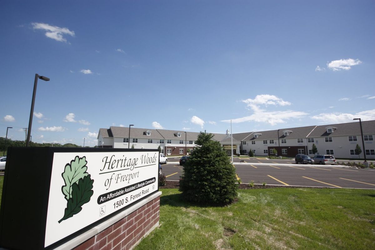A view of an apartment complex with a sign reading 'Heritage Village of Waterville' under a clear blue sky.