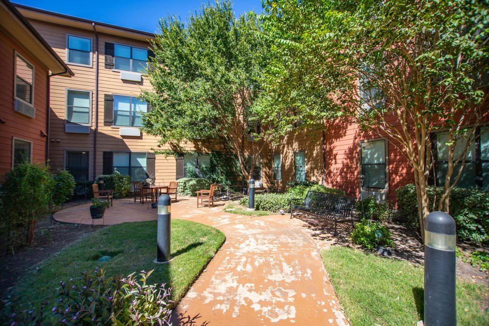 A beautiful garden path in an apartment complex surrounded by lush greenery and trees.