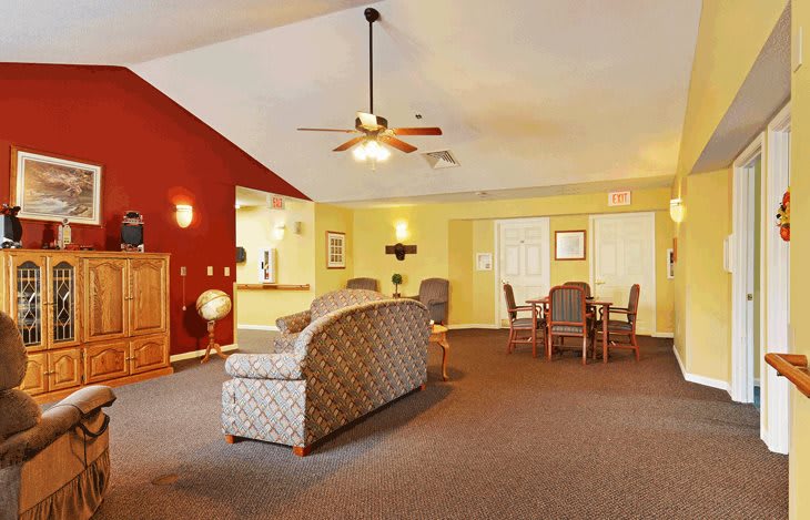 A cozy living room featuring a sofa, chairs, and a table under a ceiling fan.