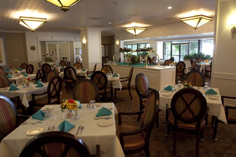 A formal restaurant dining room with elegantly set tables and chairs.