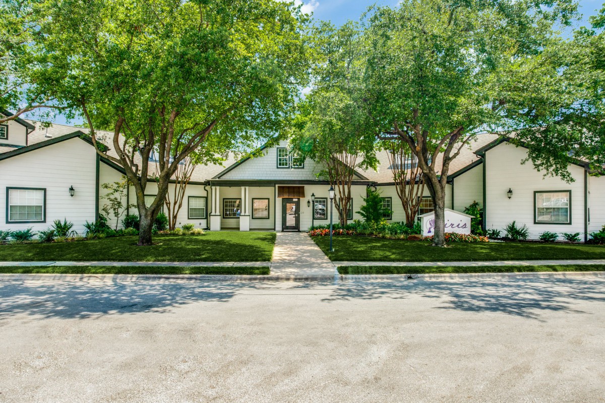 A modern residential home with a manicured lawn and surrounding trees.