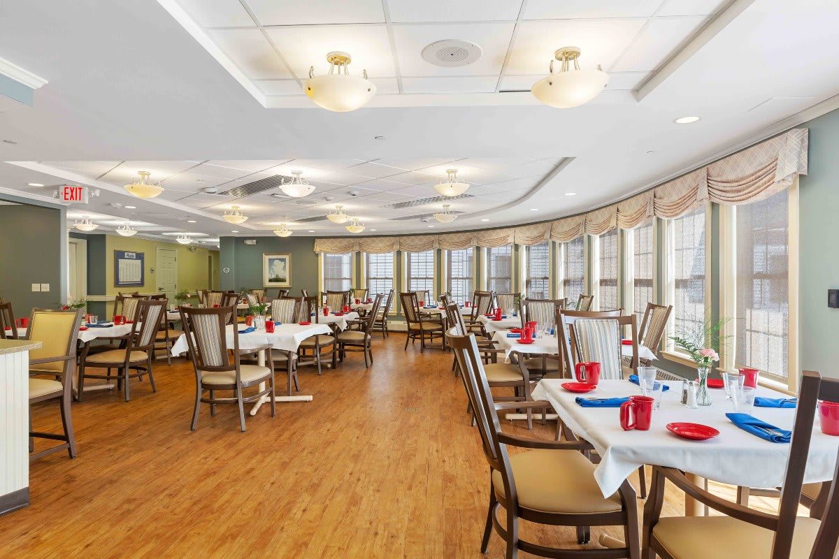 A spacious dining room with elegantly set tables and large windows.