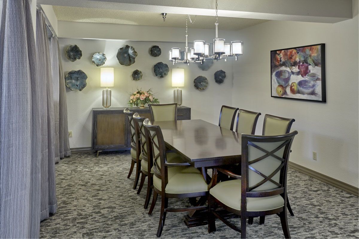 A stylish dining room featuring a long table with chairs, modern lighting, and decorative wall art.