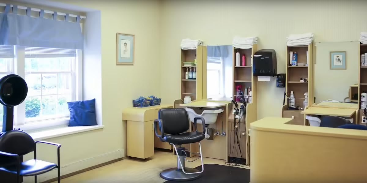 An empty hair salon with a barber chair and styling station.