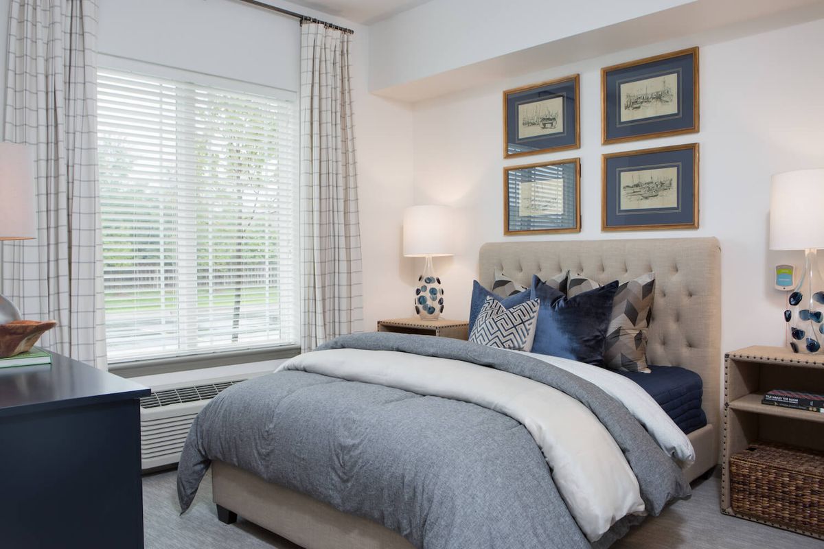A cozy and elegantly decorated bedroom with a large window and framed artwork.