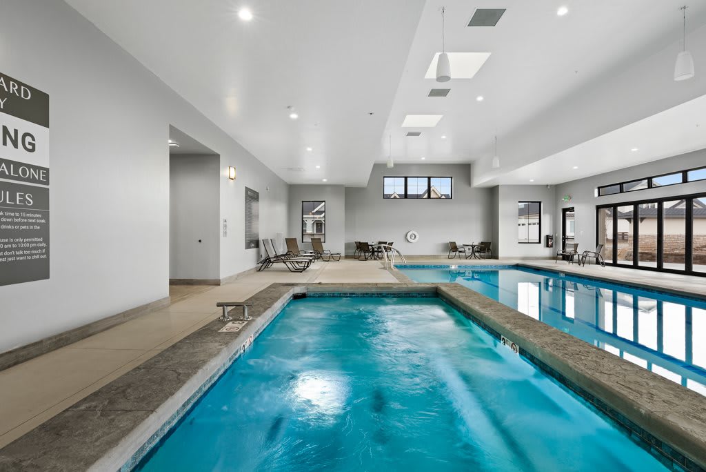 A modern indoor swimming pool with an adjacent fitness area.