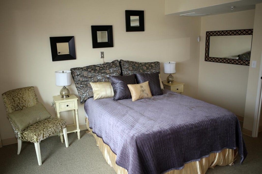 A cozy bedroom with elegant decor, featuring a bed adorned with pillows and flanked by bedside lamps.