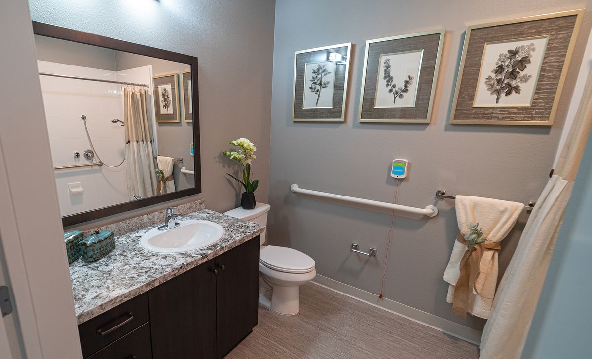 A modern bathroom with elegant decor featuring a sink, toilet, and framed artwork on the wall.