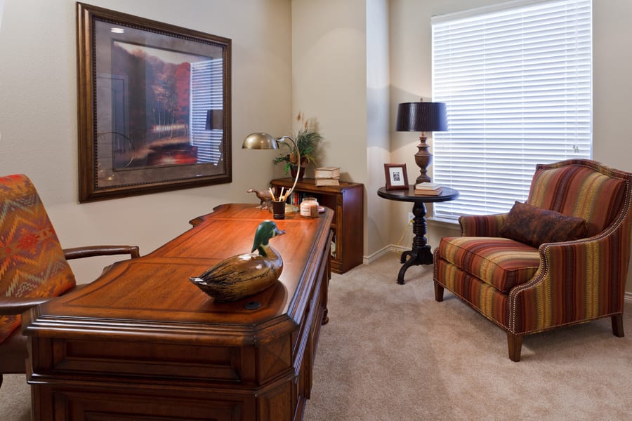 A cozy home office with a wooden desk, comfortable armchair, and ambient lighting.