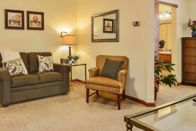 A cozy living room featuring a sofa, armchair, and warm lighting.