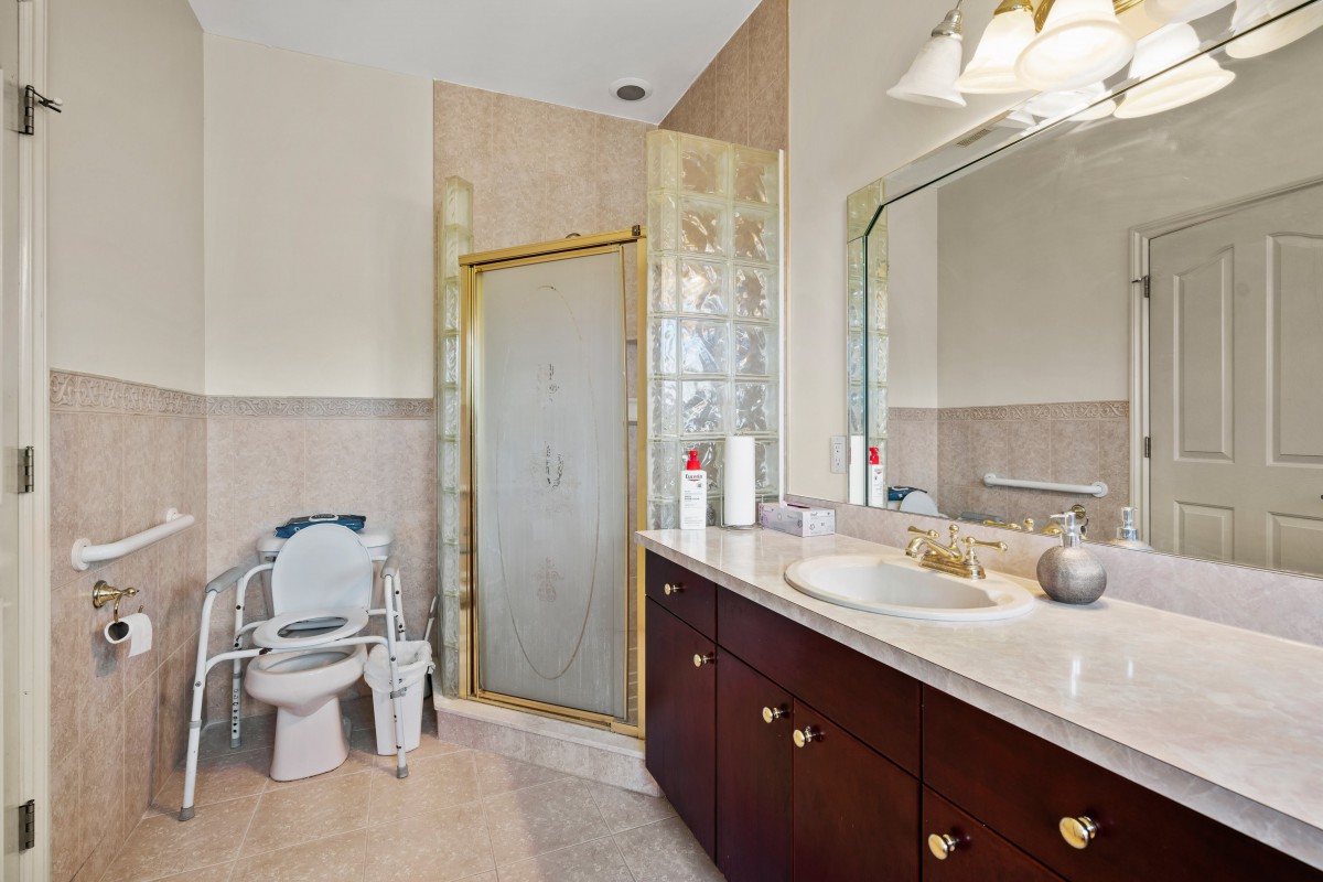 A well-lit bathroom with a glass shower, sink, and mirror.