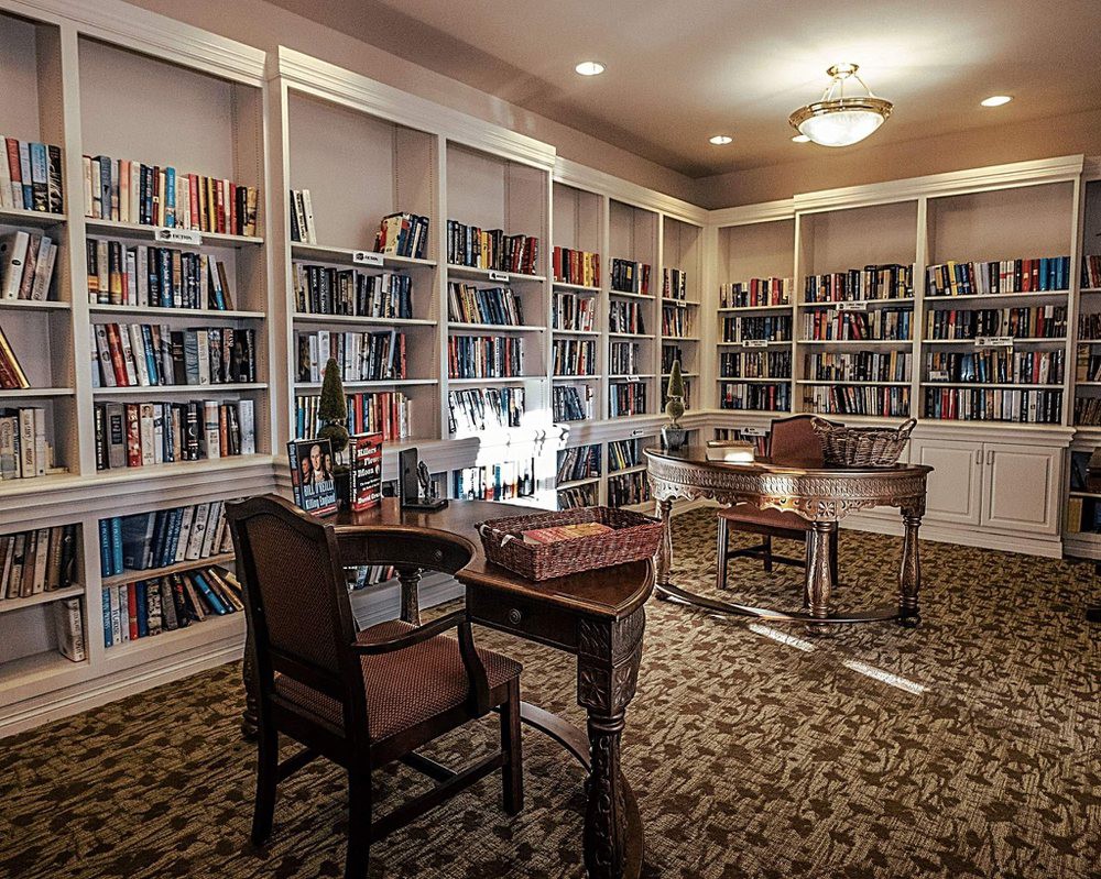 A cozy library with bookshelves, a desk, and chairs for reading.