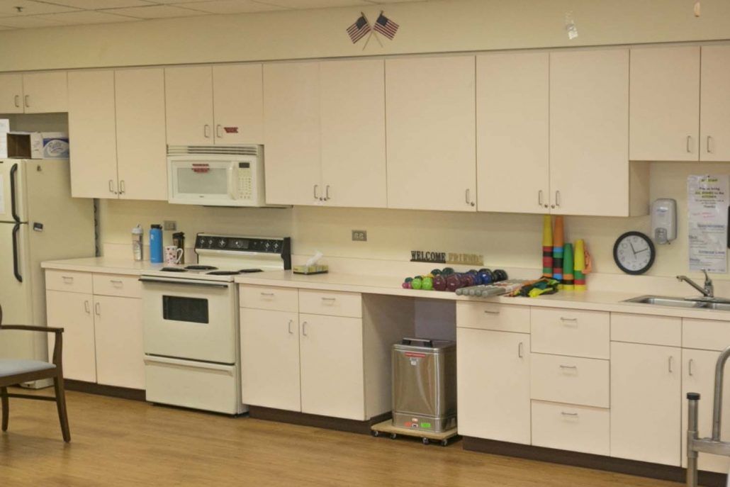 A kitchen with white cabinets, an oven, a microwave, and various items on the countertop.