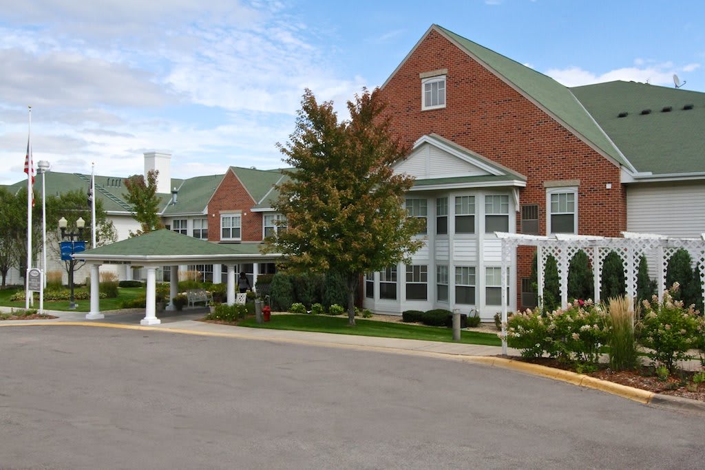 A brick residential building with green roofs and a landscaped entrance.
